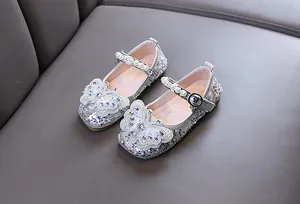 Gros plan de chaussures de princesse argentées scintillantes pour filles avec papillon