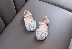 Détail de chaussures de princesse argentées pour filles avec papillon et bride en perles