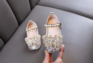 Détail de chaussures de princesse argentées à paillettes pour filles avec papillon