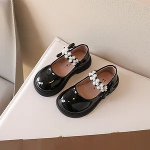 Elegantes zapatos Mary Jane de charol negro para niñas con perlas y lazo decorativo.