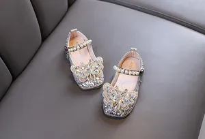 Vue détaillée de chaussures de princesse argentées avec strass et papillon en perles