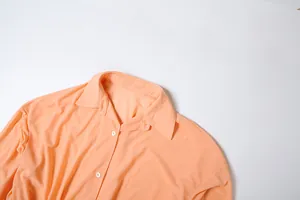 Dettaglio del colletto a punta di questo elegante abito a camicia color pesca primaverile