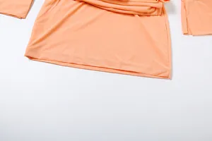 Dettaglio dell'orlo e dei polsini di un abito a camicia aderente color pesca