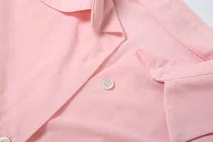 Vista ravvicinata del colletto di una camicia rosa con bottoni e trama del tessuto
