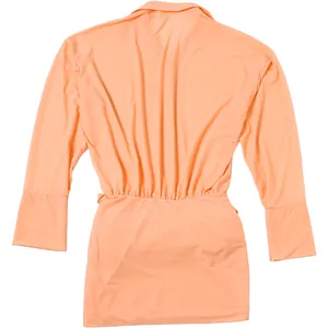 Dettaglio posteriore di un abito a camicia color pesca con vita aderente e pieghe