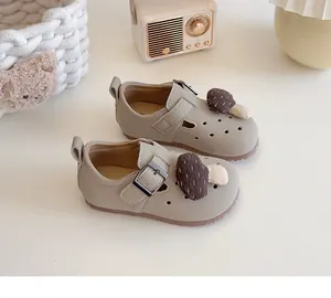 Nahaufnahme süßer beige Kleinkind-Mädchen-Lederschuhe mit Plüschpilz-Dekoration.