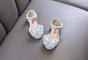 Close-up of sparkly silver girls' princess shoes with pearl straps and butterfly detail.