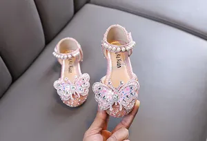 Close-up of pink girl's princess shoes with rhinestone butterfly and pearl strap