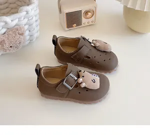 Detaillierte Ansicht der braunen Kinder-Loafer mit einem süßen Bären-Plüschornament.