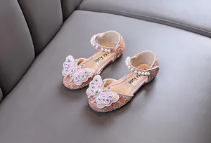 Close-up of pink girl's princess shoes with rhinestone butterfly and pearl strap