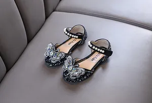 Close-up of girl's black princess shoes with rhinestones, pearls and butterfly