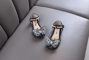 Detail of girl's black princess shoes with rhinestone butterfly and pearl strap