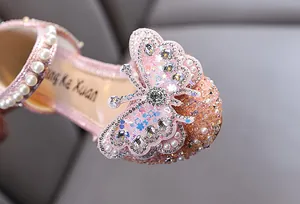 Close-up detail of a pink girl's princess shoe featuring a sparkling butterfly and pearl strap