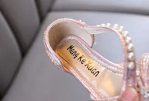 Close-up of pink girl's princess shoe showing pearl strap and glitter finish details.