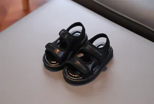 Nahaufnahme von atmungsaktiven schwarzen Kleinkindersandalen mit weichen Sohlen und Klettverschluss