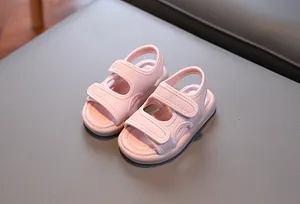 Nahaufnahme von rosa Kleinkindsandalen mit doppelten Klettverschlüssen auf grauem Grund