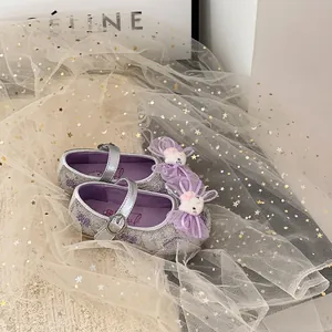 Primer plano de zapatos de princesa con purpurina plateada para bebé y lazo lila.