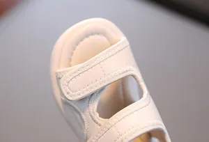 Nahaufnahme einer weißen Babysandale mit verstellbarem Klettverschluss und Nähten