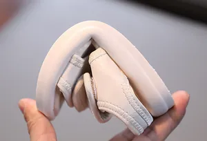 Nahaufnahme der extremen Flexibilität und weichen Sohle der cremefarbenen Kindersandale