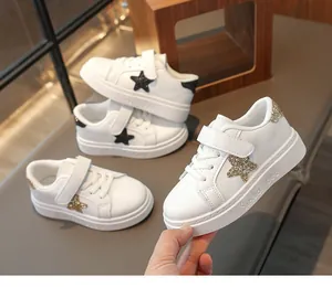 Detailopname van witte leren kindersneakers met glitterster en klittenbandsluiting