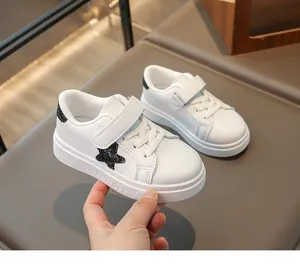 Detail van witte leren kindersneakers met een zwarte glitterster en handige klittenbandsluiting