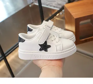 Detailweergave van witte lederen kindersneaker met een zwarte glitterster motief
