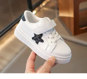 Detailopname van witte leren kindersneakers met een zwarte glinsterende ster detail.