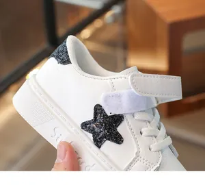 Detailopname van witte kindersneaker met glinsterende zwarte ster en klittenband