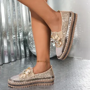 Detalle de mocasines brillantes con lazo de pedrería y suela de plataforma gruesa