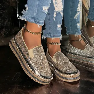 Close-up of sparkling gold sequined slip-on platform loafers with rhinestone details.