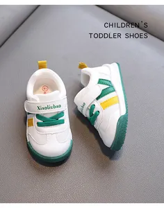 A close-up detail of white toddler walking shoes with green and yellow stripes
