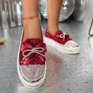 Detalle macro de mocasines rojos brillantes con lazo de pedrería y plataforma