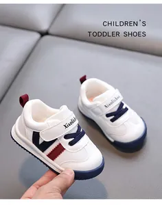 Close-up detail of white leather toddler sneakers with red and navy blue decorative stripes