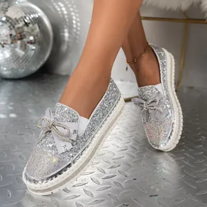 Primer plano de mocasines plateados con purpurina, plataforma y un elegante lazo de pedrería.