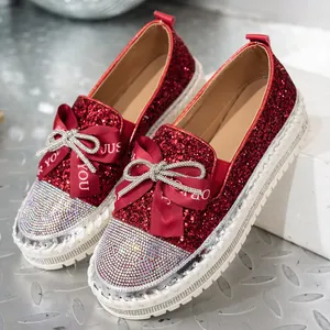 Detalle de mocasines rojos con purpurina, lazos de pedrería y suelas de plataforma gruesa.