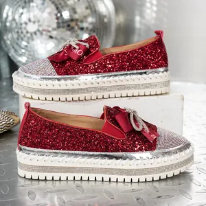 Detalle de mocasines de plataforma con purpurina roja con lazo de strass y suela blanca
