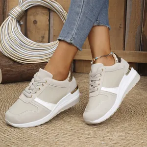 Women's beige platform sneakers with gold accents and wedge sole in a rustic setting