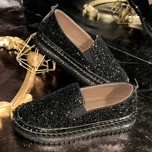 Detailed shot of black sequined platform loafers featuring sparkling rhinestone edges