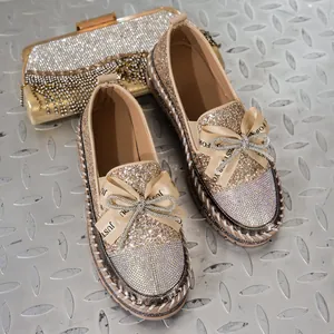 Primer plano de elegantes mocasines de purpurina con lazos de strass y bolso de mano dorado