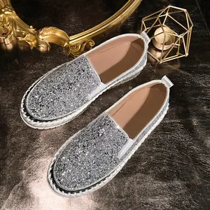 High-angle detail view of shiny silver sequin slip-on loafers with platform soles.