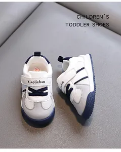 Detailed view of white toddler sneakers with grey suede accents and navy blue soles