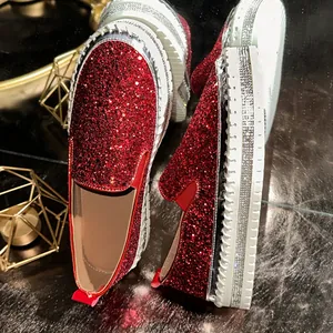 Close-up of red sequined slip-on loafers with rhinestone-studded thick white soles