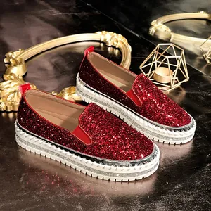 Close-up detail of red glitter slip-on loafers featuring sparkling rhinestone platform soles.