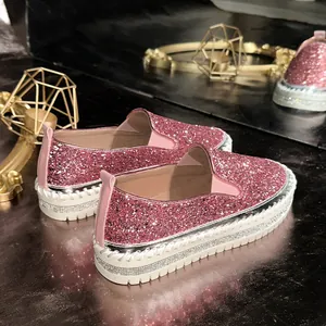 Detail shot of pink glitter slip-on platform shoes with rhinestone welt trim.
