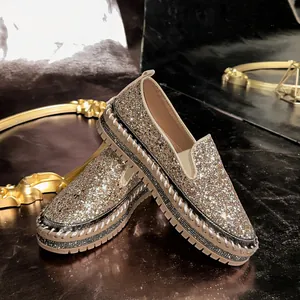 Close-up of glittery platform slip-on shoes with rhinestone welt and metallic sequins.