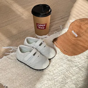 Dettaglio di scarpe primi passi bianche per neonati su un tappetino morbido e accogliente