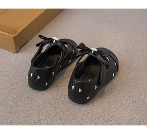Detalle posterior de zapatos de princesa negros para niña con corazones y lazo