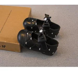 Detalle de zapatos de princesa negros para niña con lazo y estampados de corazones