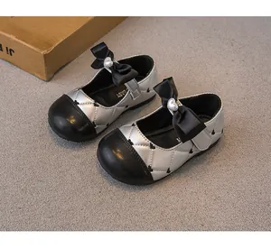 Primer plano de zapatos de princesa plateados acolchados con lazo negro y perla de corazón.