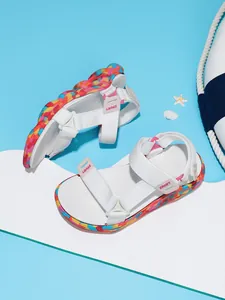 Gros plan de sandales de plage pour filles avec brides blanches et semelles camouflages.